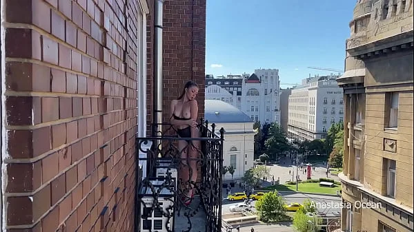 A woman undresses on a balcony in the city center. Public flashing.